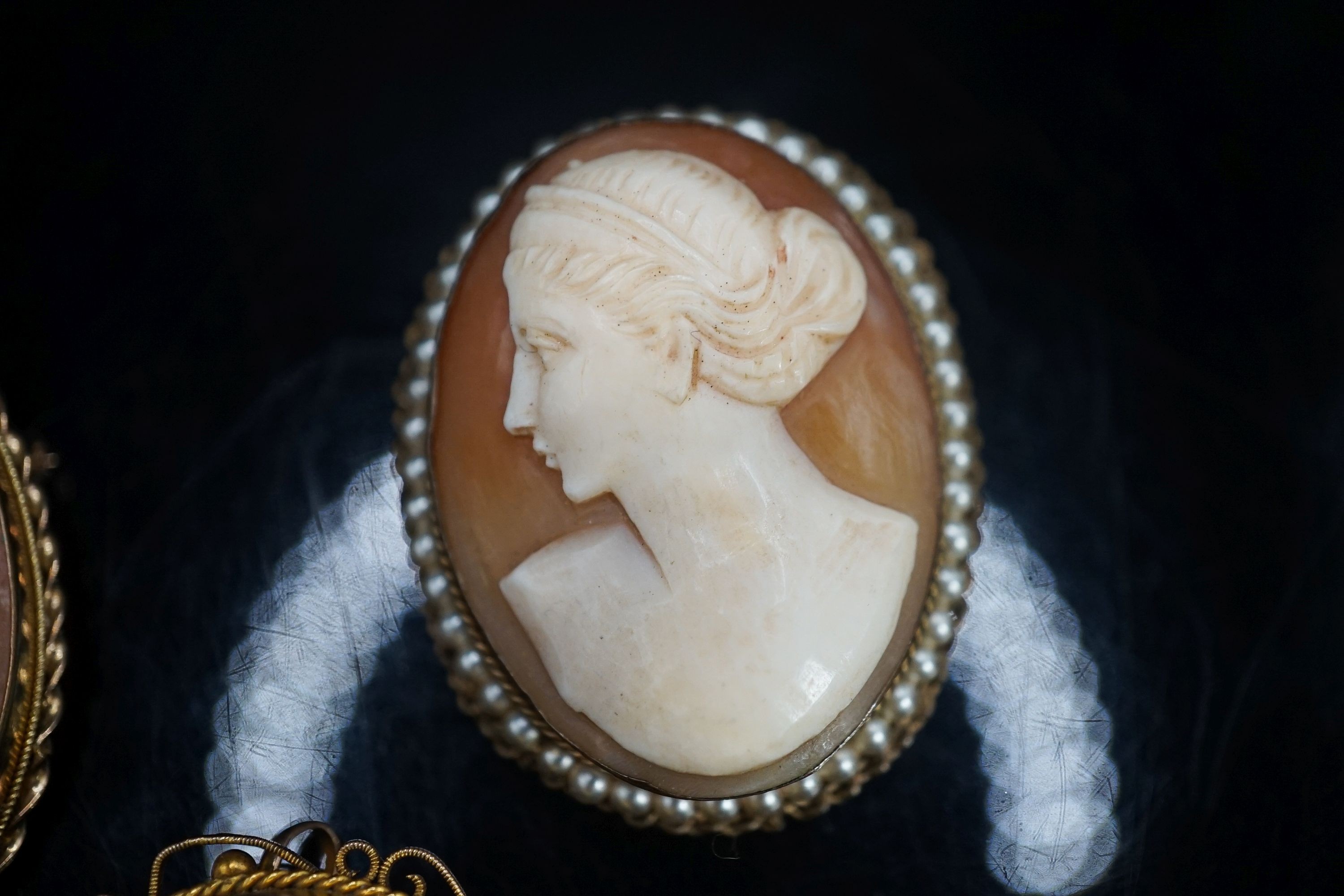 A Victorian 9ct mounted oval cameo shell brooch, one other later 9k mounted cameo brooch and a gilt metal mounted cameo brooch.